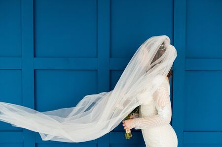 gorgeous bride with transparent veil on a background of blue wall.の写真素材