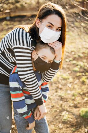 Caring mother hugs a masked child to protect him from the virusの写真素材