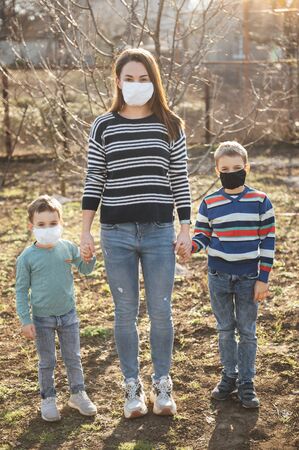 A loving mother holds and hugs her children. They wear protective masks against the virus.の写真素材