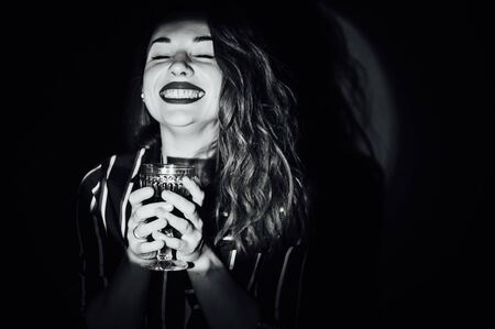 girl on green background with a glass of red drink wine smoke looks asideの写真素材