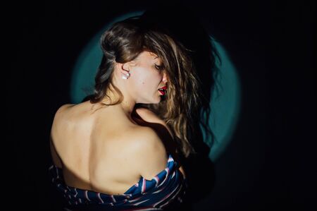 very beautiful girl posing with her back to the camera on a green backgroundの写真素材