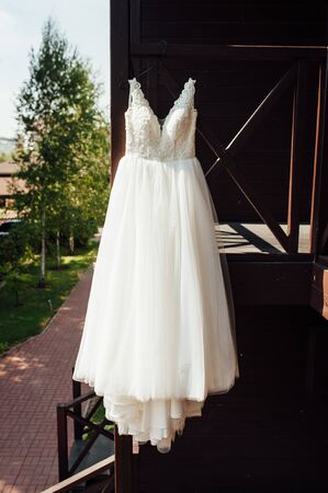 Elegant wedding dress hanging on a wooden railing outsideの写真素材