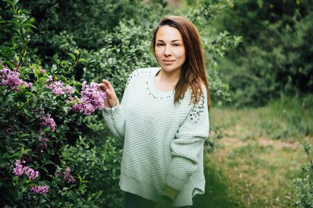 Outdoor fashion photo of beautiful young woman surrounded by flowers. Spring blossomの写真素材