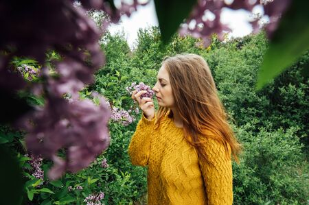 Outdoor fashion photo of beautiful young woman surrounded by flowers. Spring blossomの写真素材