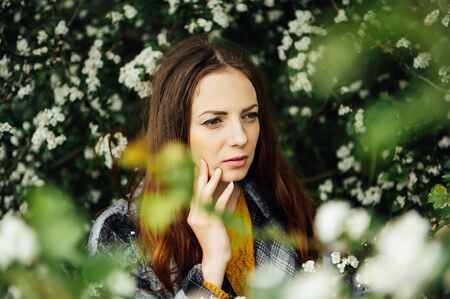 Outdoor fashion photo of beautiful young woman surrounded by flowers. Spring blossomの写真素材