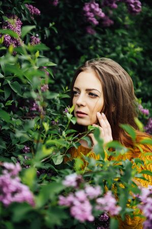 Outdoor fashion photo of beautiful young woman surrounded by flowers. Spring blossomの写真素材