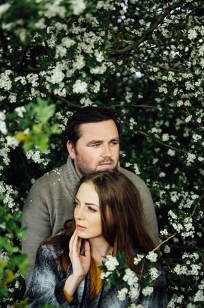 Beautiful couple in love is hugging near a white flowers bush. lifestyle photoの写真素材