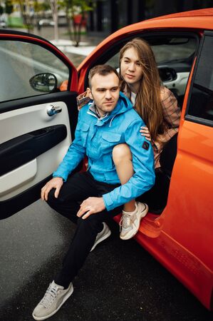 beautiful cheerful couple hugging in a red carの写真素材