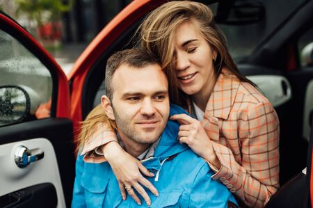 beautiful cheerful couple hugging in a red carの写真素材