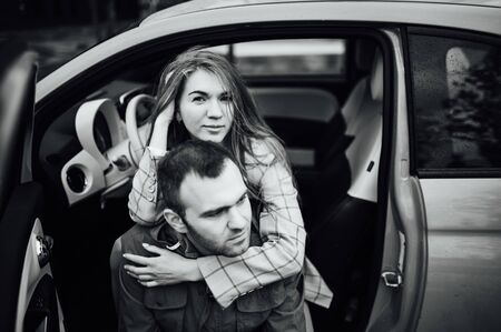beautiful cheerful couple hugging in a red carの写真素材