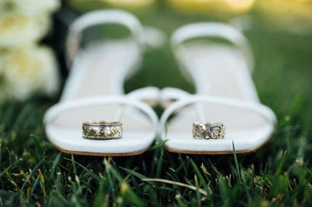 Beautiful white gold wedding rings lie on bridal shoesの写真素材