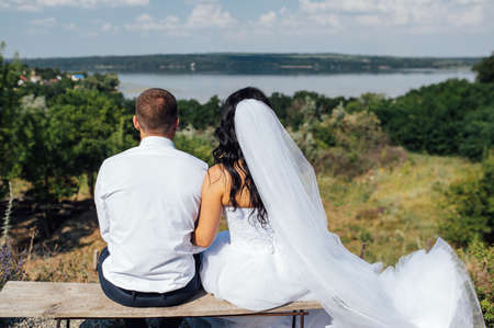 wedding Bride and groom on a bench with nature landscape scenery backgroundの写真素材