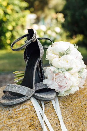 Wedding bouquet of peonies next to womens shoes on a stoneの写真素材