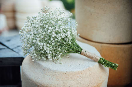 A beautiful wedding bouquet of gypsophila lies on a clay jugの写真素材