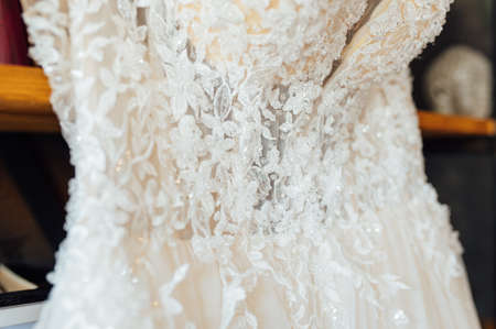 A chic silk wedding dress hangs on a bookcase.の写真素材