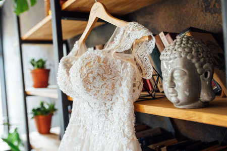 A chic silk wedding dress hangs on a bookcase.の写真素材