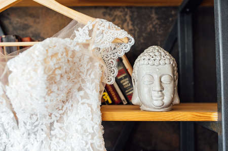 A chic silk wedding dress hangs on a bookcase.の写真素材