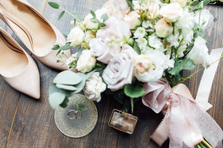 Luxurious wedding bouquet next to the rings of the bride and groom. The brides shoes with heelsの写真素材