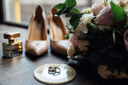 Luxurious wedding bouquet next to the rings of the bride and groom. The brides shoes with heelsの写真素材