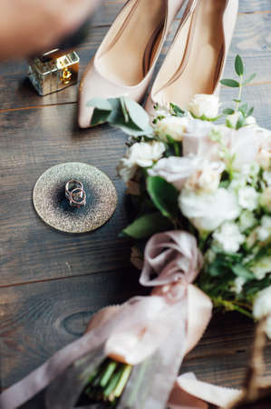 Luxurious wedding bouquet next to the rings of the bride and groom. The brides shoes with heelsの写真素材