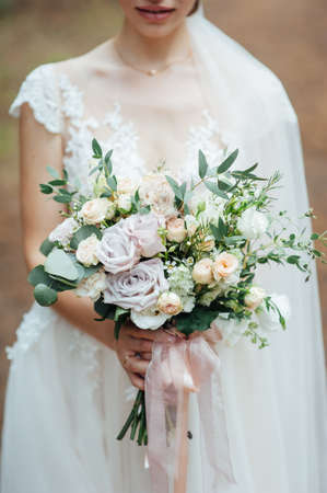 beautiful wedding bouquet in the hands of the bride in the forestの写真素材