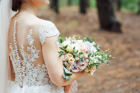 beautiful wedding bouquet in the hands of the bride in the forestの写真素材