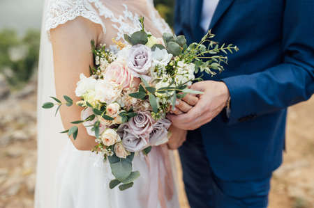 happy bride and groom hugging with a bouquet in their handsの写真素材