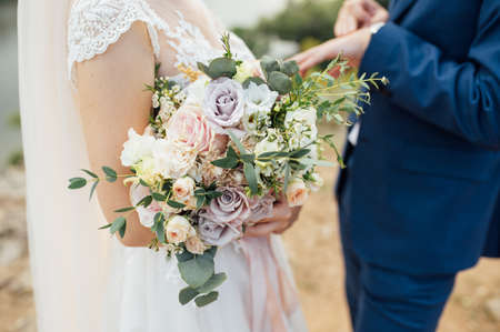 happy bride and groom hugging with a bouquet in their handsの写真素材