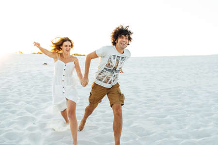 Cheerful couple in love running on the beach and enjoying their vacationの写真素材