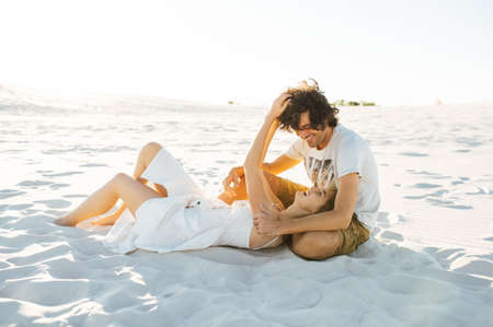 A mischievous girl lies on the lap of her beloved and holds him by the hair.の写真素材