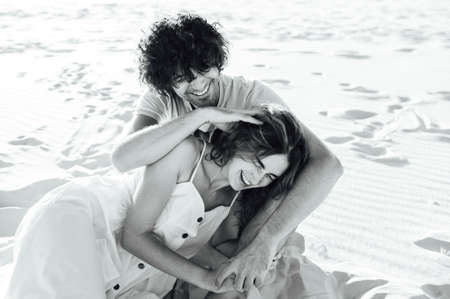 A curly-haired guy and a beautiful girl are having fun on the beachの写真素材