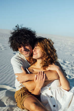 A curly-haired guy and a beautiful girl are having fun on the beachの写真素材