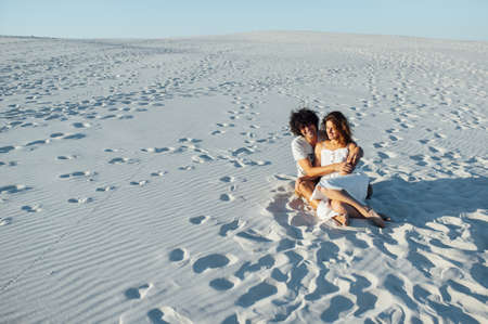 A curly-haired guy and a beautiful girl are having fun on the beachの写真素材