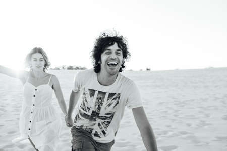 Cheerful couple in love running on the beach and enjoying their vacationの写真素材