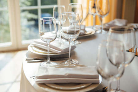 Luxurious restaurant. Luxurious interior, white tables, serving dishes and glasses for guestsの写真素材