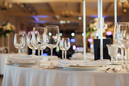 Luxurious restaurant. Luxurious interior, white tables, serving dishes and glasses for guestsの写真素材