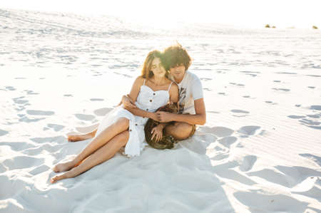 Cheerful young couple having fun on the beach with their bengal catの写真素材