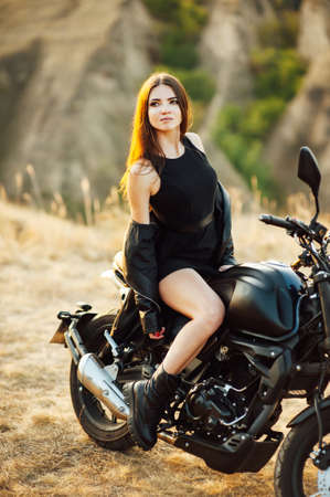 Girl on a motorcycle. She is beautiful, posing on a motorcycle at sunsetの写真素材