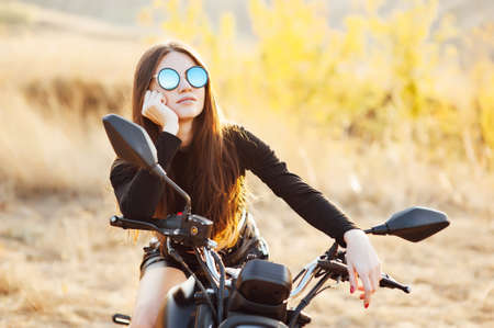 beautiful fashionable woman on a classic motorcycle, model appearance with sunglassesの写真素材