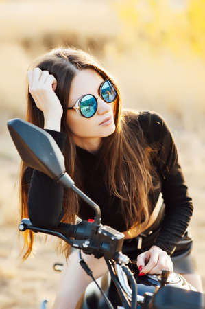beautiful fashionable woman on a classic motorcycle, model appearance with sunglassesの写真素材
