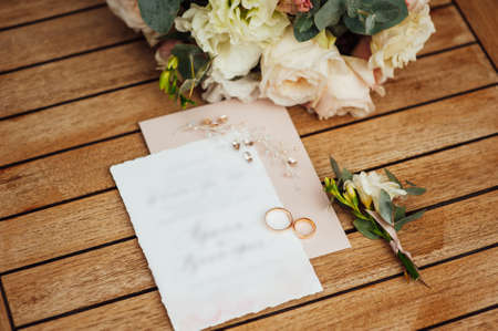 Wedding invitation letter for newlywed guests. The rings and the bridal bouquet lie side by sideの写真素材
