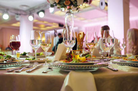 Luxurious restaurant. Luxurious interior, white tables, serving dishes and glasses for guestsの写真素材