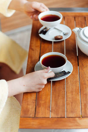 A loving couple sits in dressing gowns and drinks tea on a wooden tableの写真素材