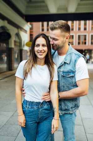 Fashion outdoor romantic portrait of beautiful young couple in love and hugs on the street.の写真素材