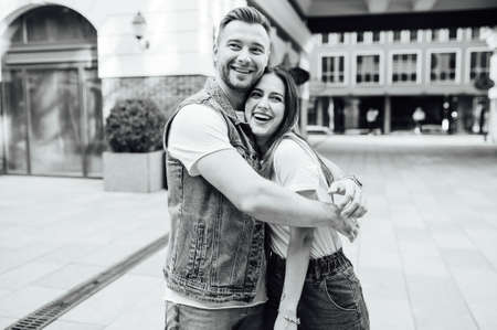 Fashion outdoor romantic portrait of beautiful young couple in love and hugs on the street.の写真素材