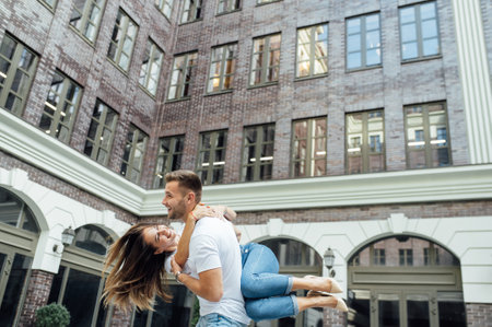 Fashion outdoor romantic portrait of beautiful young couple in love and hugs on the street.の写真素材