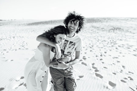 a guy with curly hair and his girlfriend are hugging cheerfully on the sandの写真素材