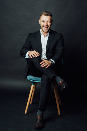 Handsome businessman man sitting on chair in photo studioの写真素材