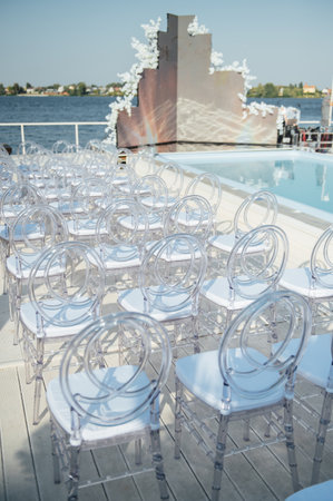 Glass chairs stand in a row in a beautiful wedding outing ceremonyの写真素材