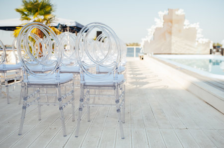 Glass chairs stand in a row in a beautiful wedding outing ceremonyの写真素材
